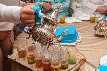 A Moroccan man pours tea into cups. Moroccan mint tea