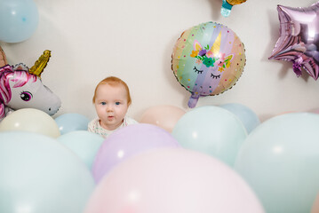 Happy baby celebrates her birthday. Party decoration with balloons in the style unicorn, rainbow,...