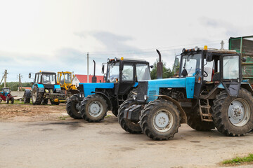 Obraz premium Agricultural machinery, tractors and equipment outdoors, near the garage, ready to work in the field.