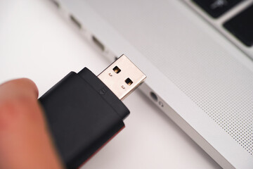 A USB Flash Drive in person hand and laptop near