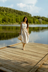 Fototapeta na wymiar Young woman walking on the wooden pier at the calm lake