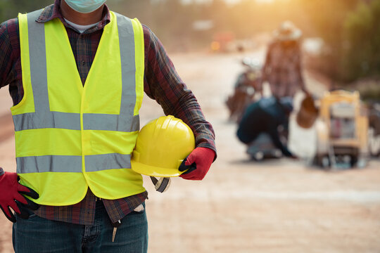 worker in uniform holding helmet in the road construction