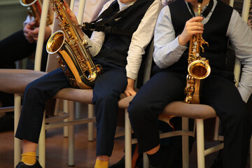 Young musicians with a musical instrument a golden saxophone sitting in the hall resting in a free pose close-up conceptual image of youth education and leisure