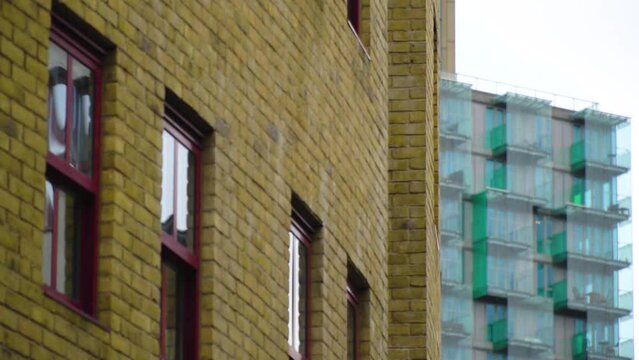 spectacular panning shot in between buildings uncovering modern building with lots of balconies in cloudy british weather 5d moving shot