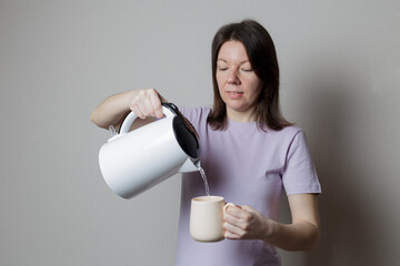 girl pours water from a kettle into a cup - Powered by Adobe