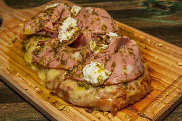 Mortadella and cheese pizza sprinkled with different aromatic herbs and served on a wooden board