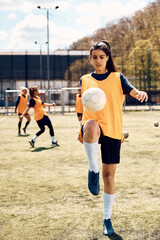 Female soccer player practicing with ball during sports training on stadium.