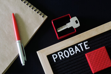 The inscription probate on a black board next to a notepad, pen and key in a red gift box. The...