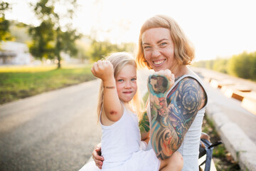 Mom hugs and holds her daughter in her arms, funny emotional mom and daughter show fists at the...