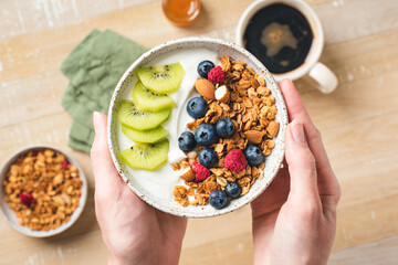 Yogurt and granola bowl with berries in female hands. Eating healthy food, clean eating, dieting...