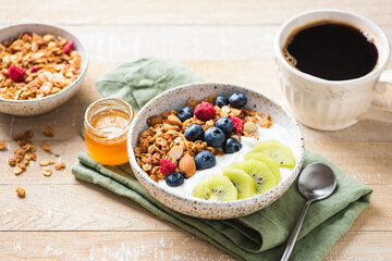 Granola bowl with greek yogurt, blueberries and kiwi on wooden table. Healthy breakfast food