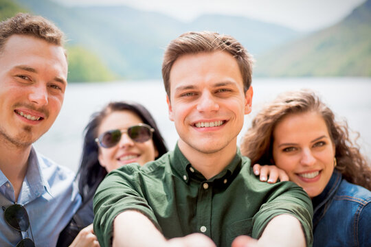 Smiling young friends taking selfie outdoors on sunny day in a beatiful tourist location