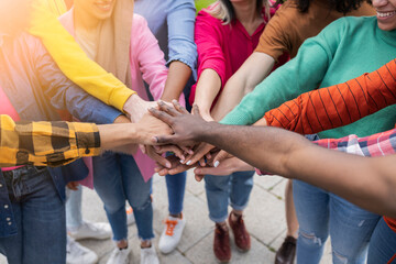 multiracial friends putting their hands together - Teenagers standing together in cooperation -