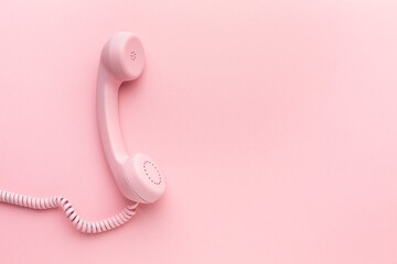 Pink telephone receiver on pink background