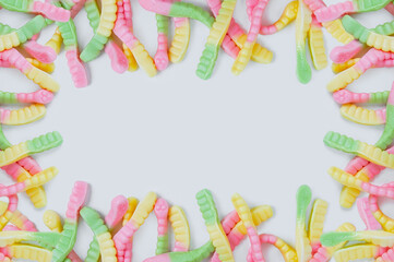 Frame of bright colored chewing candies in form of worms. White background. Place for text.