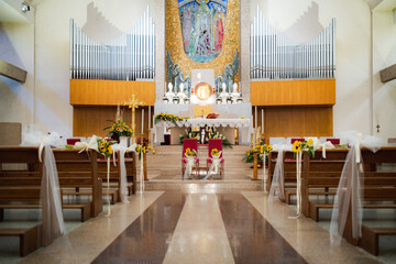 Fototapeta na wymiar Horizontal view of a modern catholic church with central altar and wood benches decorated for a wedding ceremony