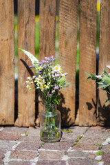 Glass jars containing wildflowers in front of some wooden boxes used as decoration for a wedding 