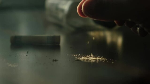 Drug addict pouring white powder of cocaine or heroin on the table for consumption, close-up. The concept of drug addiction and social degradation