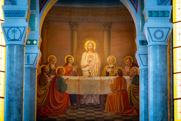 Fresco representing Jesus holding the host in his hands surrounded by the apostols during the last supper. Inside of a catholic church - 505231637