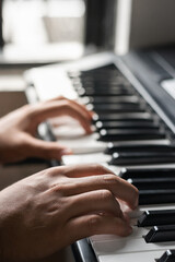 Obraz premium detailed view of the hands of a young dark-haired man playing the electronic piano or synthesizer. latin man practicing his hobby at home. composing or harmonizing a song.