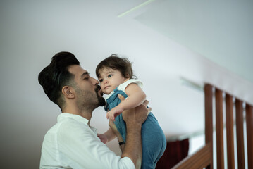 Cute little toddler baby boy playing and chewing marker pen with father while looking away and thinking at home