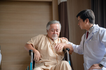 Fototapeta premium Senior male patient sitting on wheelchair in hospital smiling and talking and showing something outside the window to handsome doctor in labcoat