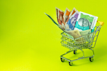 Miniature shopping trolley with Colombian money. The concept of shopping and the power of the economy. Place for text