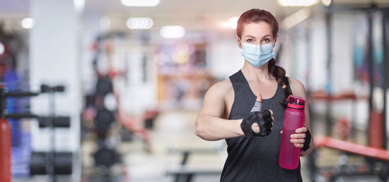Fitness trainer with a mask on his face shows good with his hand .