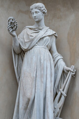 Old statue of Italian or Greek woman holding an industrial gear in historic downtown in Potsdam,...
