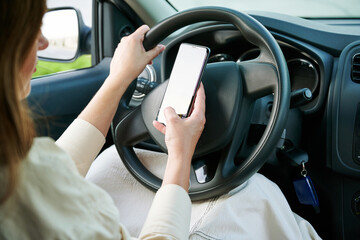 No cell phone use while car driving. Woman driver holding mobile phone a steering wheel in a new...