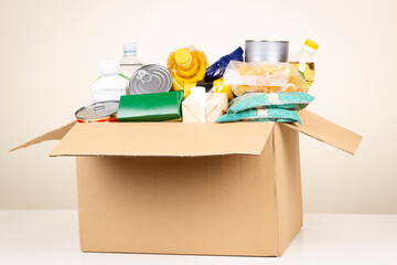 Cardboard box with grocery products. Volunteer collecting food into donation box. Donation,...