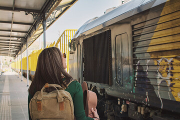 Rear view of a woman traveling with a backpack  at a train station. Travel Concept. Image with copy...
