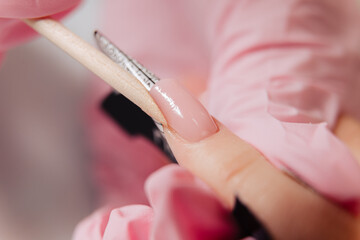Manicure process. The master forms an artificial nail from a special gel using a bamboo stick.