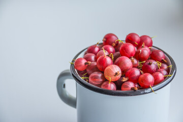 Set of organic Gooseberries fruits in a cup. red gooseberry over white background. Sweet and juicy berry. healthy summer food. they are good for vision, immunity, cognitive abilities