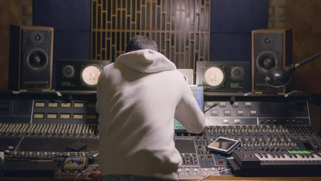 Man working at music recording studio, making arrangements and listening to music using samplers and other special recording equipment. Music production concept