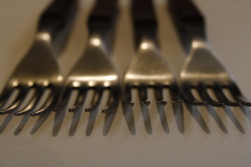 Tenedores para utensilios de cocina en hilera con desenfoque hacia atràs, con luz incidente forman brillos y reflejos con sombra muy bonito para fondos de diseños