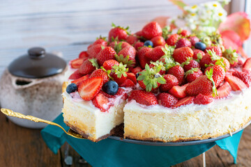vanilla coconut cheesecake, decorated with fresh strawberries, a cup of aroma coffee on a table