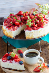 vanilla coconut cheesecake, decorated with fresh strawberries, a cup of aroma coffee on a table