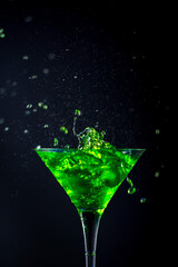 Green soft drink with splashing soda in a glass