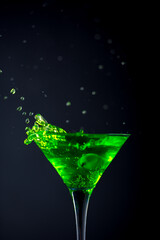 Green soft drink with splashing soda in a glass