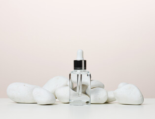 White glass transparent bottle with a pipette for cosmetics, oils, acids on a white table