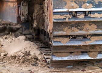 A closeup photograph of the track of an old large industrial yellow bulldozer machine weathered, rusty and worn sitting on a beach in Chicago. © Joseph Kirsch