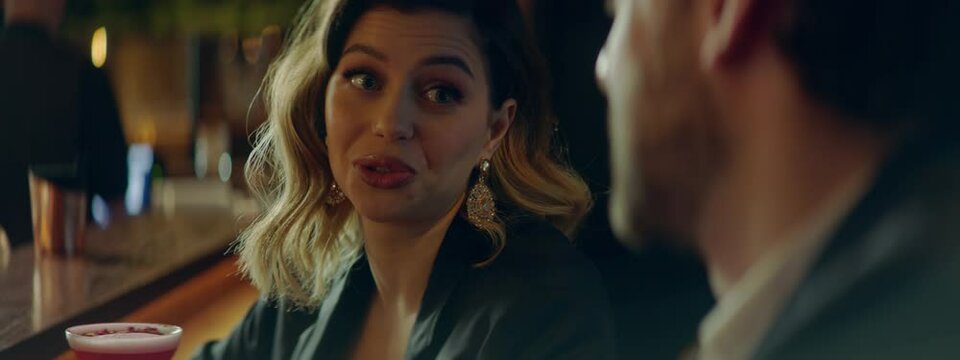CU Portrait of beautiful Caucasian couple having a date in a stylish restaurant, talking and laughing. Shot with 2x anamorphic lens