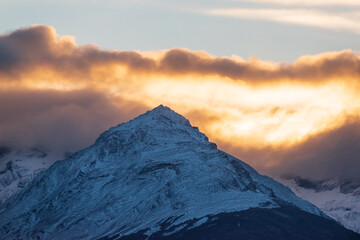 cima de montana nevada con nubes de atardecer, ocaso entre montañas 