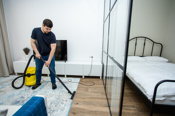 an experienced young guy cleans the floor with a professional vacuum cleaner