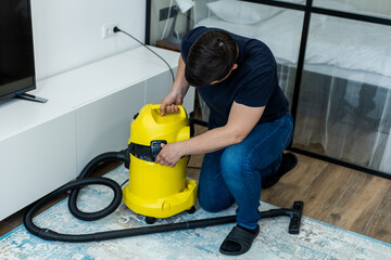 professional cleaner vacuuming carpet and floor with yellow vacuum cleaner