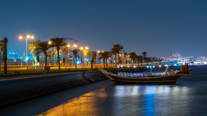 View of qatar Corniche during night with a colorful decorated traditional dhow