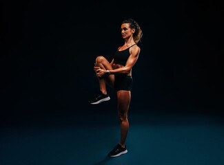 Sports woman doing flexibility exercises. Young female runner stretching her leg.