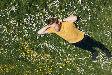 Young man laying in green grass with flowers. People fatigue from work. Summer sleeping and...
