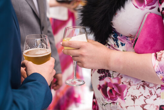 Detalle de una mujer y un hombre sosteniendo dos copas con bebida durante la celebraci&oacute;n de un evento. Concepto de beber alcohol durante el embarazo.